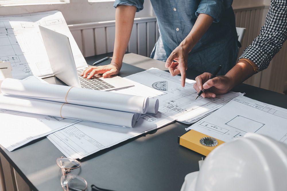 Architects two man discuss drawing blueprints together at office.